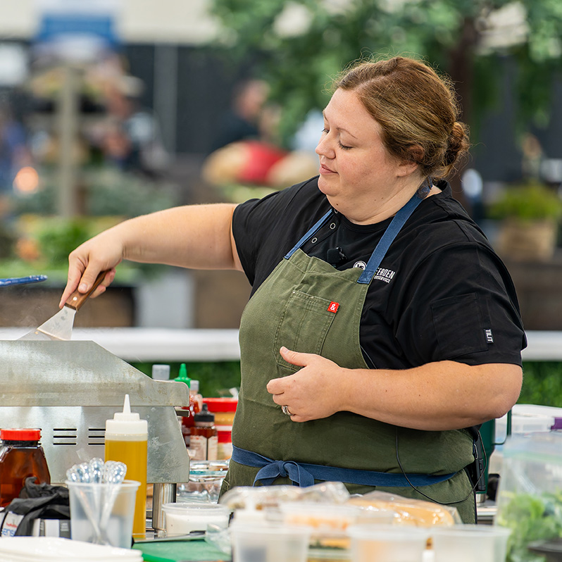 Skilled chef grilling outdoors in vibrant culinary event, showcasing passion and expertise.