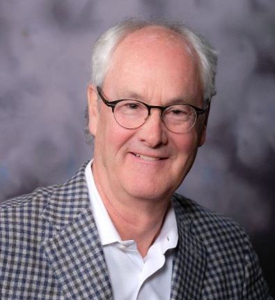 Warm-hearted professional man in glasses and stylish blazer, exuding confidence and friendliness.