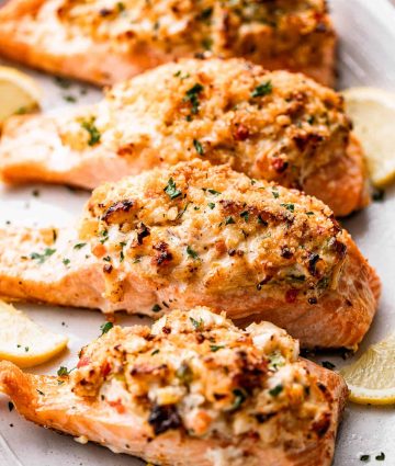 Crispy herb-topped baked salmon served with lemon wedges on an elegant platter.