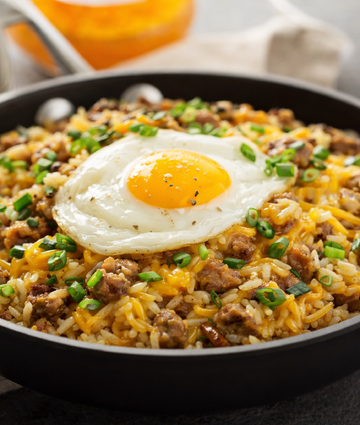 Cheesy rice skillet with ground meat, scallions, and a sunny-side-up egg.