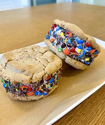 Colorful cookie sandwiches bursting with sweetness and playful toppings on a rustic plate.