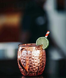 Copper mug cocktail with lime and straw, perfect for refreshing summer drinks.
