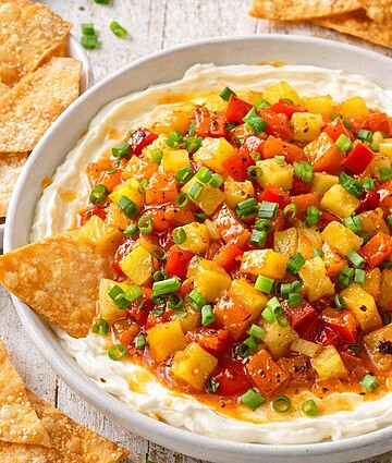Creamy corn salsa dip with diced corn, red peppers, and green onions served with crispy tortilla chips for foodservice and wholesale distribution.