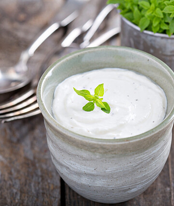 Creamy horseradish sauce in a cup, garnished with fresh herbs, perfect for dipping.