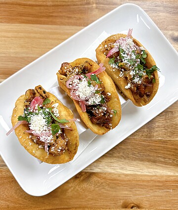 Crispy tacos filled with savory meat, cheese, cilantro, and vibrant pickled onions.