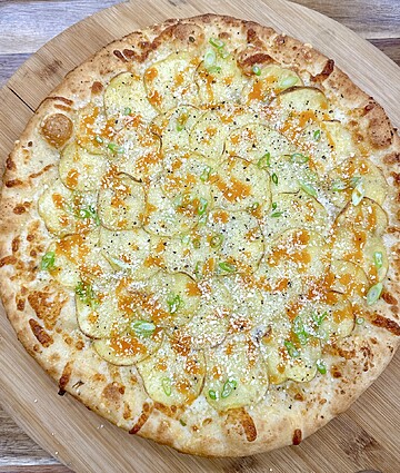 Artisanal pizza topped with creamy potatoes, melted cheese, and fresh green onions on a crispy crust.