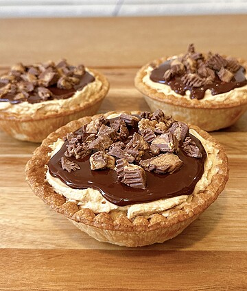 Indulgent dessert cups with creamy ganache and rich chocolate toppings on a flaky crust.