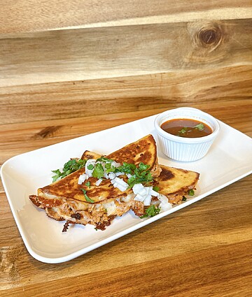 Grilled tortillas served with a savory dipping sauce and fresh toppings for a flavorful meal.