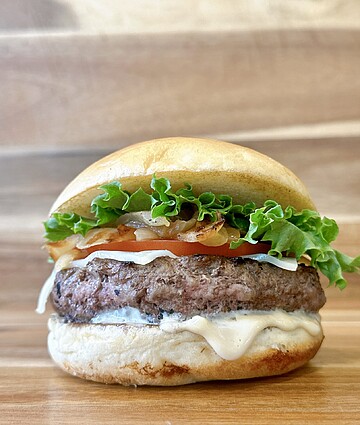 Delicious juicy hamburger with fresh toppings on rustic wood background.
