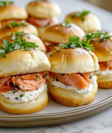 Elegant mini brioche sliders with smoked salmon and herbed cream cheese, perfectly presented on a white platter.