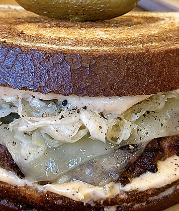 Gourmet Reuben sandwich featuring sliced corned beef, creamy dressing, and tangy sauerkraut on toasted rye bread for foodservice distribution.
