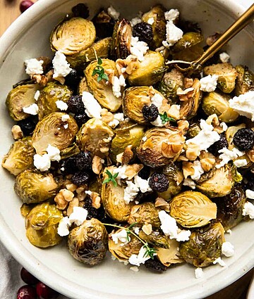Savory roasted Brussels sprouts with cheese, walnuts, and dried fruit in a rustic setting.