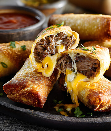 Crispy cheese steak egg rolls with savory beef and tangy dipping sauce.
