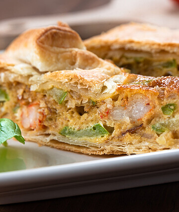 Savory shrimp, zucchini, and egg pie slices on a rustic wooden background.