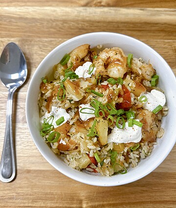 Delicious shrimp fried rice bowl topped with fresh veggies and creamy sour cream.