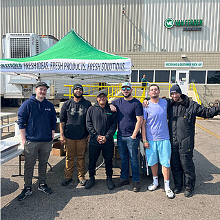 Professional foodservice distribution team posing together at Van Eerden facility event, showcasing wholesale food supplier operations and staff.