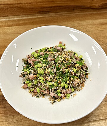 Colorful ham and pea salad, beautifully presented in a white bowl on a wooden surface.