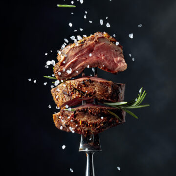 Savory grilled meat on a fork, garnished with rosemary and salt, perfect for gourmet dining.