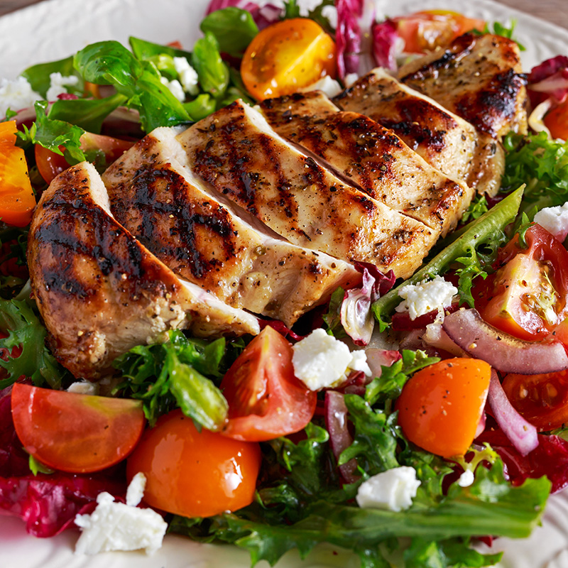 Grilled chicken salad with mixed greens, cherry tomatoes, feta, and a zesty dressing.