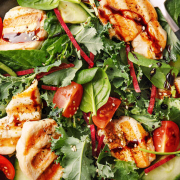 Grilled chicken salad with fresh greens, cherry tomatoes, and savory dressing for a healthy meal.