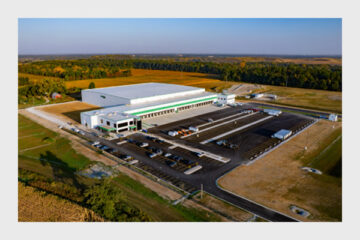 Contemporary industrial facility set against a scenic autumn landscape and farmland.