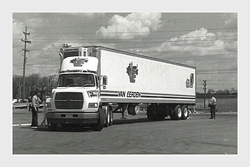 Van Eerden freight truck being inspected by workers in a busy industrial area.